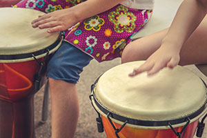 Close up of children drumming using their hands.