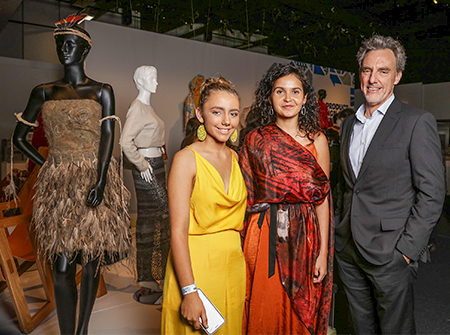 A female student has designed an interpretation of an australian indgenous possum cloak and is pictured at the opening night of an exhibition with a woman from the indigenous art community and ceo of the vcaa