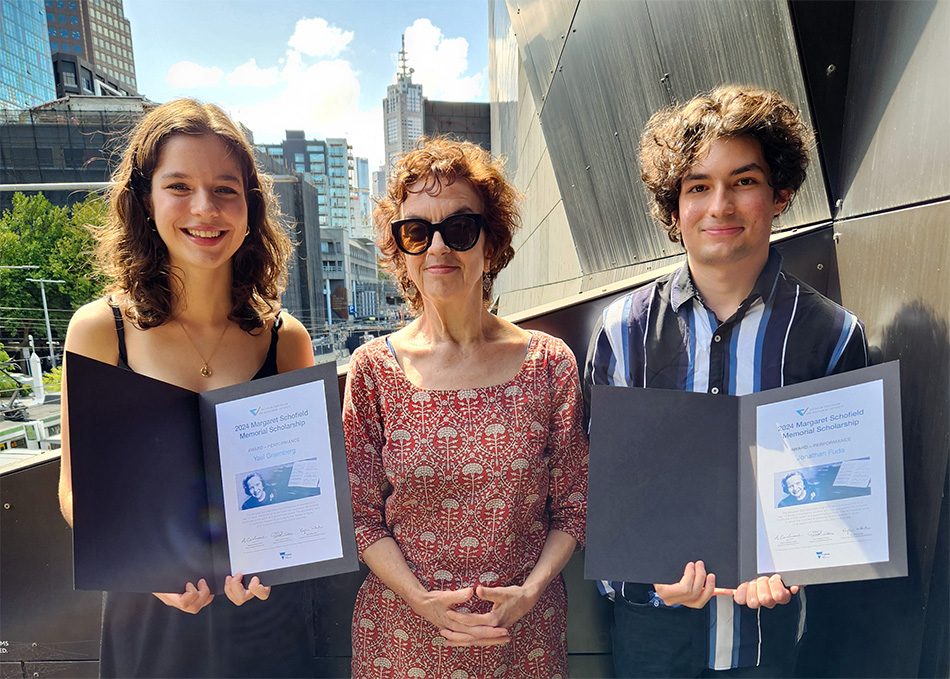 Three people stand shoulder to shoulder, all smiling. The people on the left and right are holding scholarship certificates.