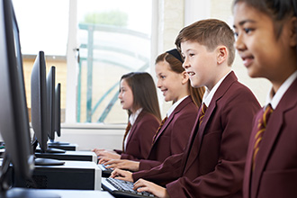 A group of young school children at their school computers